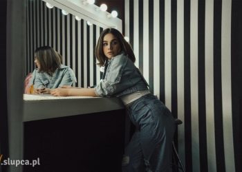 Kobieta stojąca przy lustrze z żarówkami