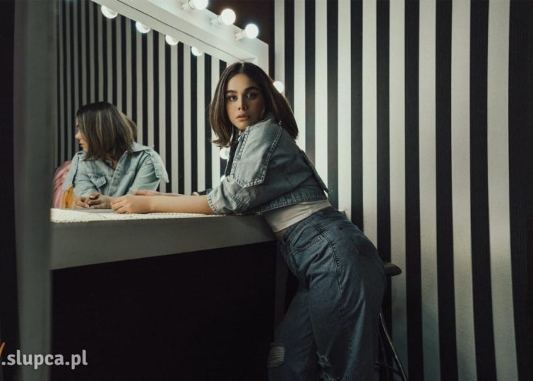 Kobieta stojąca przy lustrze z żarówkami