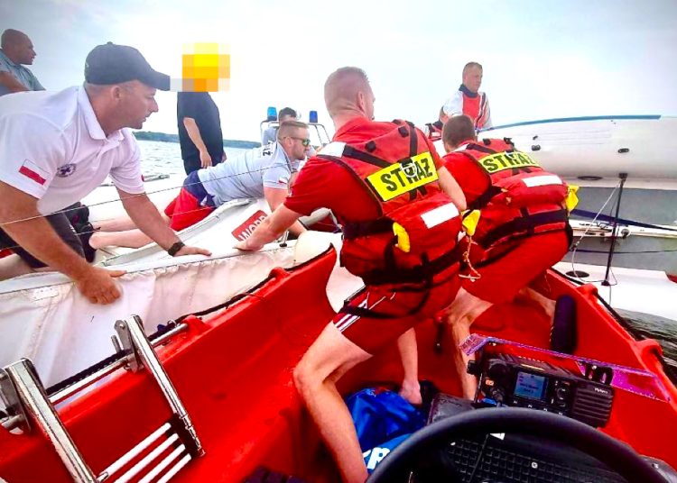 Wywrócona żaglówka, dwie osoby w wodzie