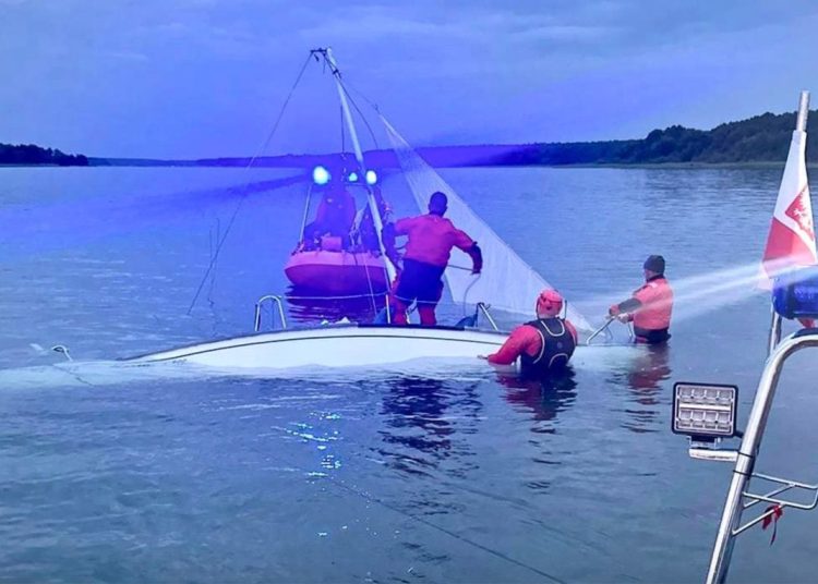 Wywrócona łódź, dwie osoby w wodzie