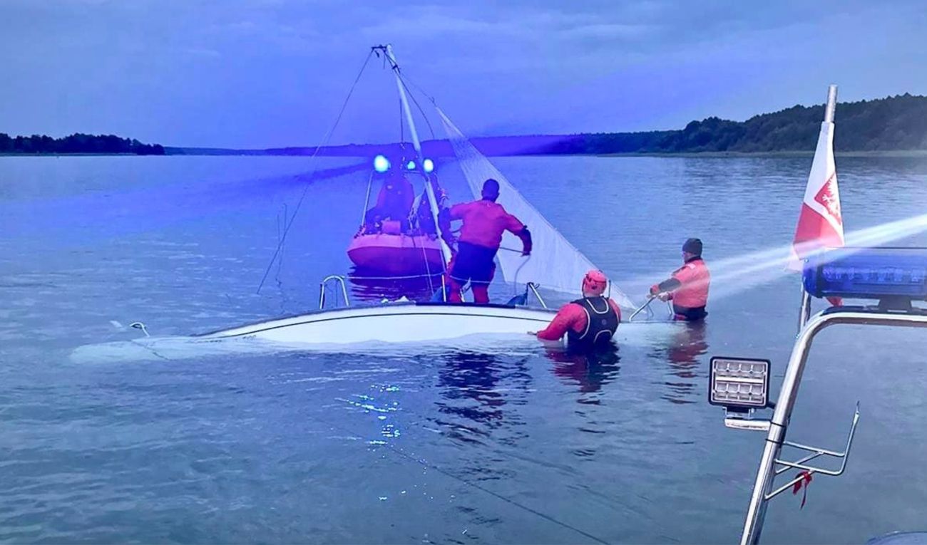 Wywrócona łódź, dwie osoby w wodzie