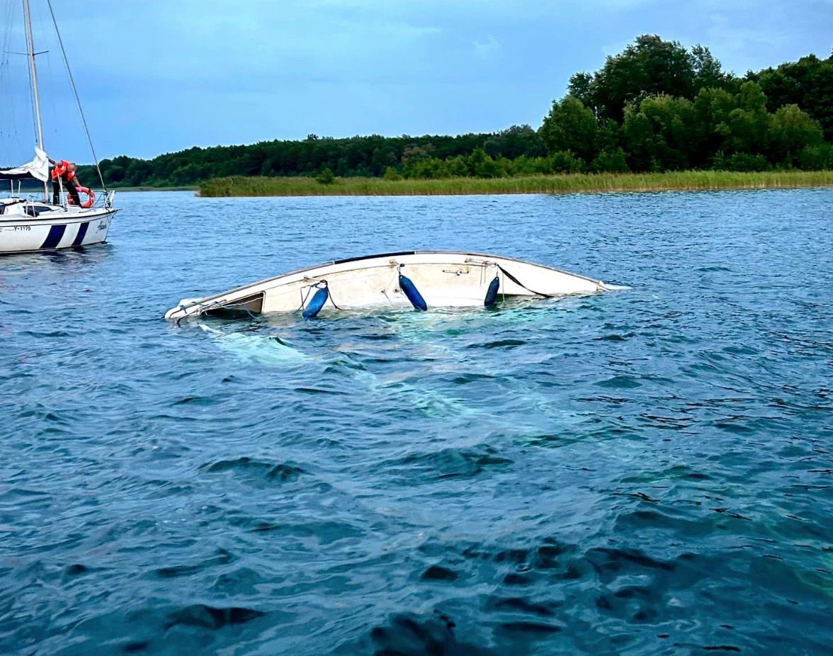 Wywrócona łódź, dwie osoby w wodzie